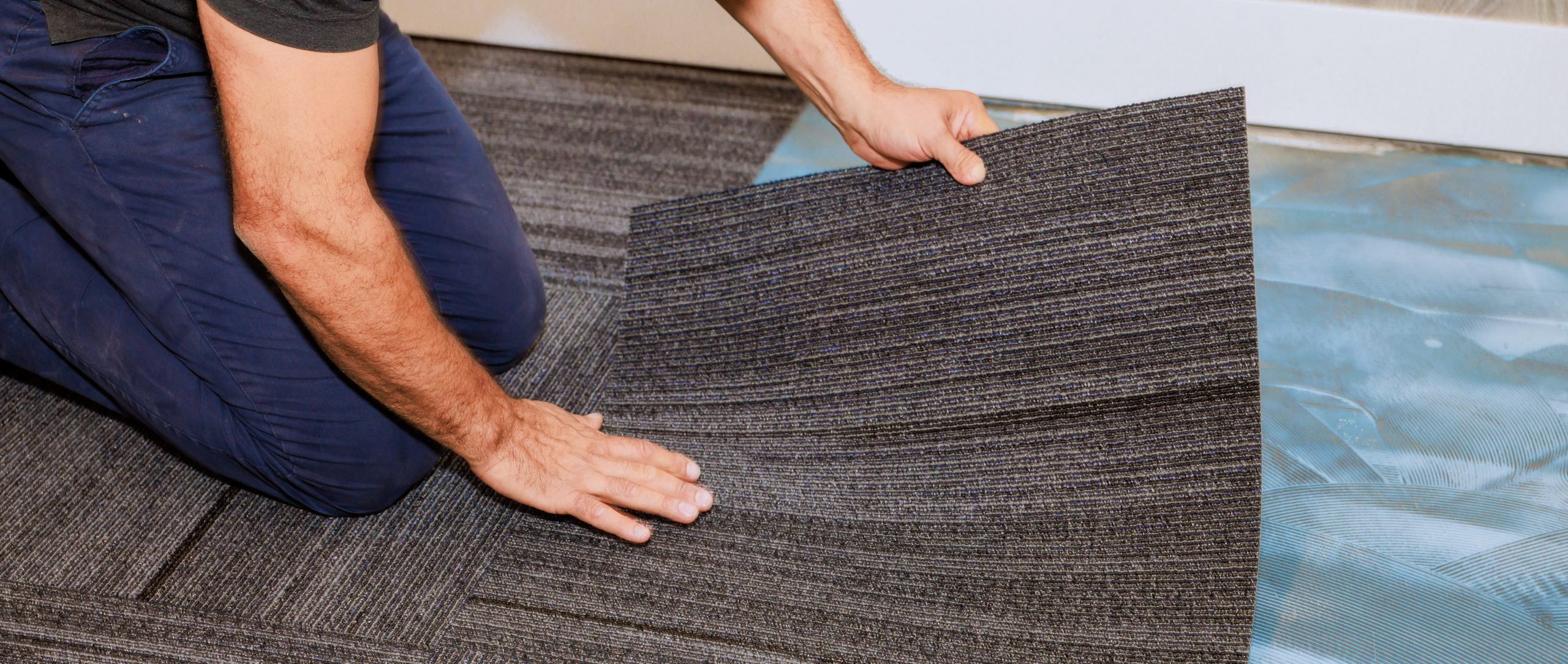 human installing carpet tiles on the floor